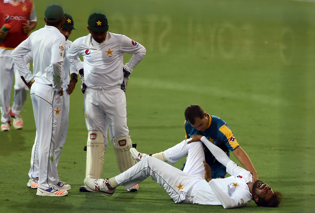 Pakistan's paceman Mohammad Amir reacts in pain at the boundary line during the first day-night cricket Test between Australia and Pakistan in Brisbane on December 15, 2016. (AFP / SAEED KHAN)