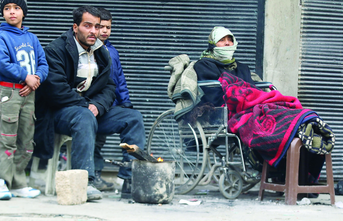 People warm themselves around a fire while waiting to be evacuated from a rebel-held sector of eastern Aleppo in Syria yesterday. 