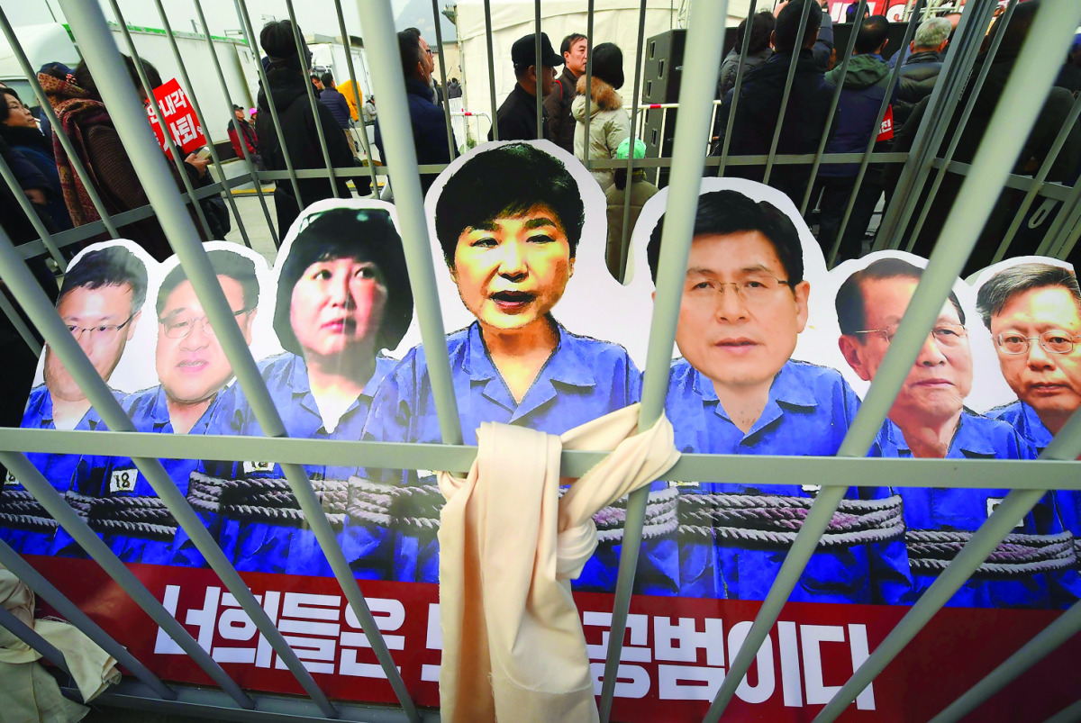 Portraits of South Korea's President Park Geun-hye and her aides are set in a mock prison during a rally in Seoul, yesterday.