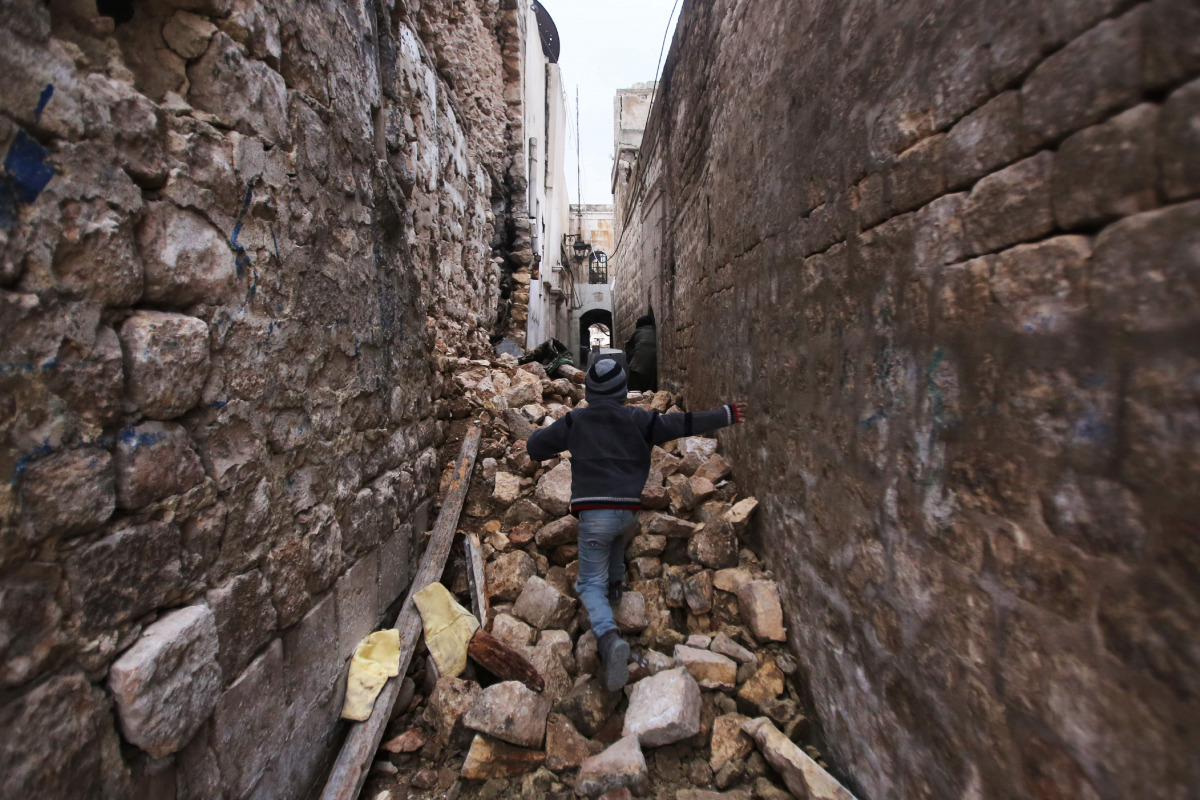 A Syrian boy makes his way through the rubble of destroyed buildings as he heads to his house in Aleppo's Dahret Awad neighbourhood on December 17, 2016, after pro-government forces retook the area from rebel fighters. / AFP / Youssef KARWASHAN