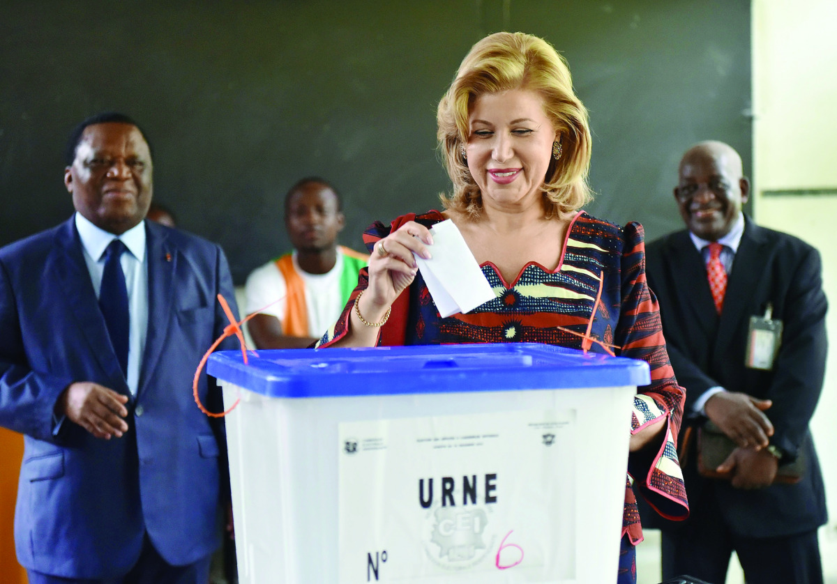 Ivory Coast's First Lady Dominique Ouattara casts her ballot next to the President of the Independent Election Commission Youssouf Bakayoko (left) at a polling station in Cocody, a commune of Abidjan, yesterday.