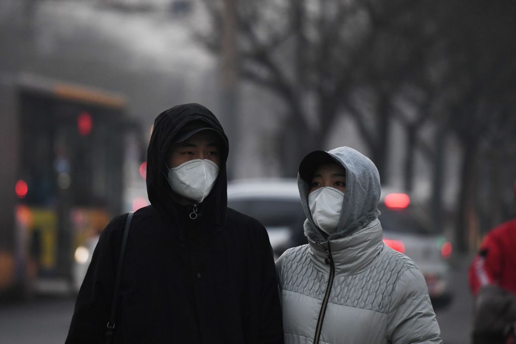 Pedestrians wear masks to protect themselves from pollution in Beijing on December 19, 2016. Hospital visits spiked, roads were closed and flights cancelled on December 19 as China choked under a vast cloud of toxic smog, with forecasters warning worse wa