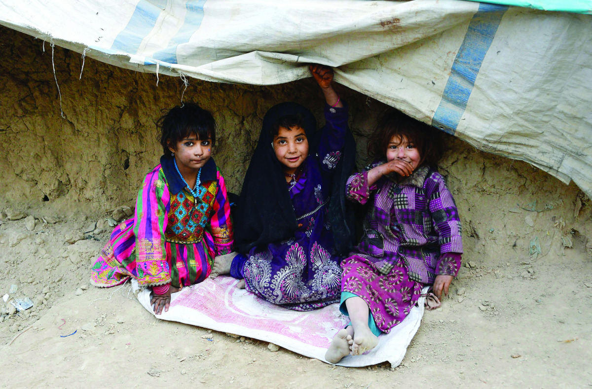 Internally displaced Afghan children sit outside their temporary home at a refugee camp in Kabul yesterday. 