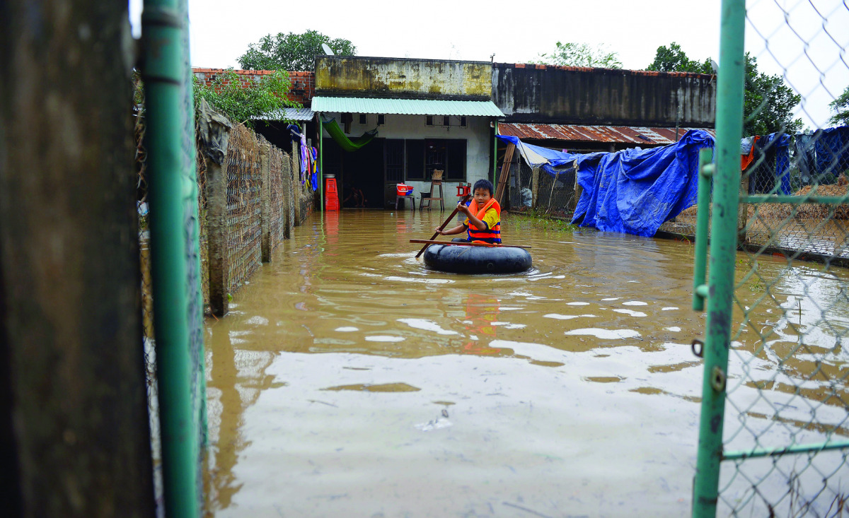 A boy leaves his flooded home on a rubber tyre tube in the central province of Binh Dinh.