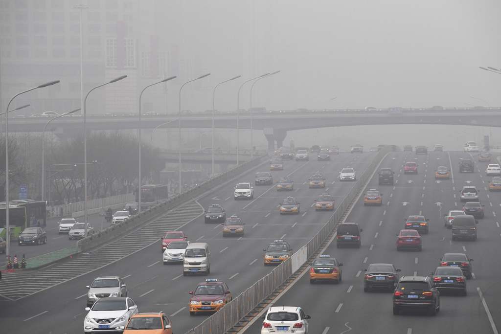 Smog hangs over a road on a polluted day in Beijing on December 20, 2016. AFP / Greg Baker
