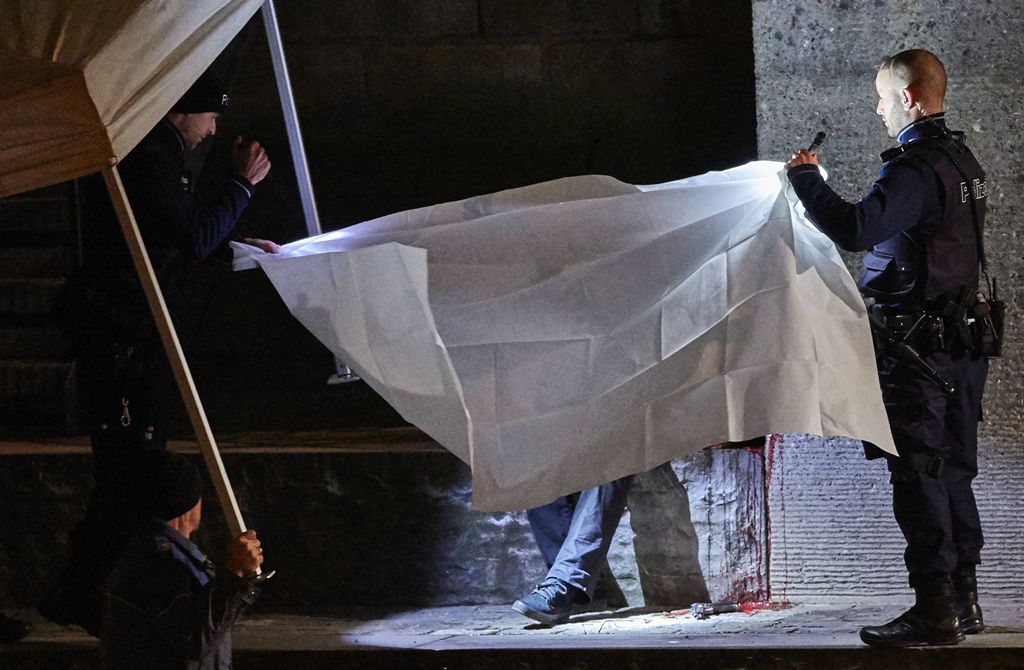 Swiss police officers hold a blanket to cover a dead body found near a Muslim prayer hall, central Zurich, on December 19, 2016, after three people were injured by gunfire. Local media reported the incident occurred in the Muslim prayer hall near the city