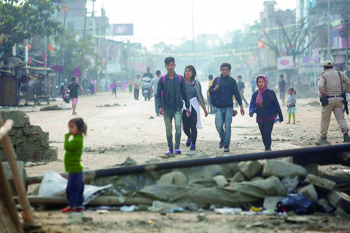 Pedestrians walking past temporary roadblocks on the outskirts of Imphal, yesterday.