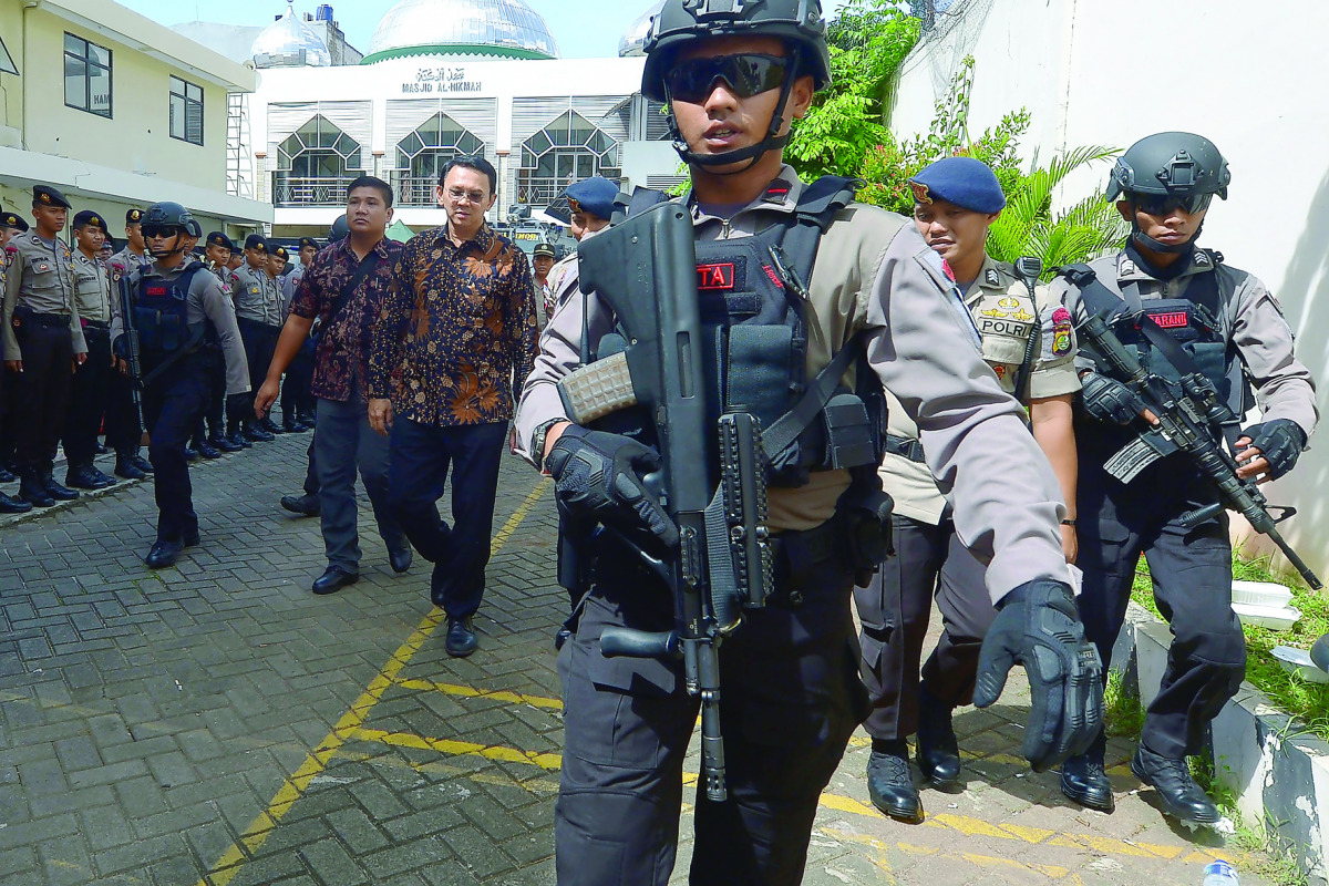 Jakarta's governor Basuki Tjahaja Purnama is escorted by anti-terror police as he leaves the North Jakarta court, yesterday.