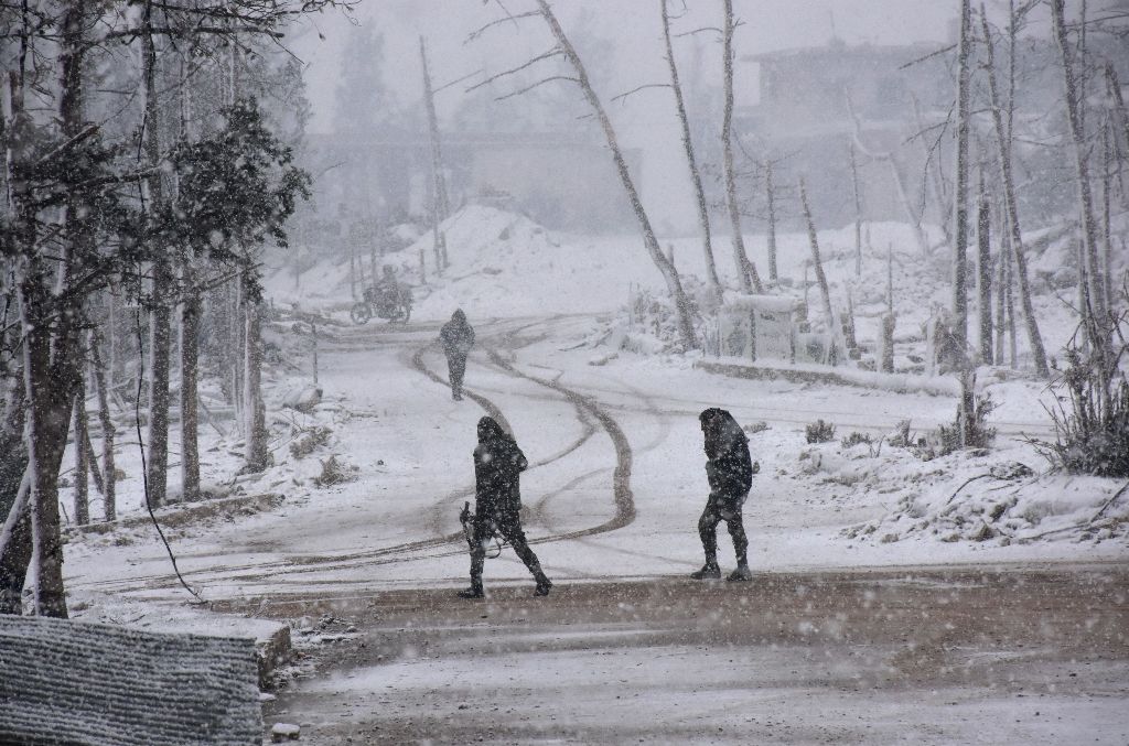Syrian pro-government forces walk as snow falls in Aleppo on December 21, 2016.    AFP / GEORGE OURFALIAN

