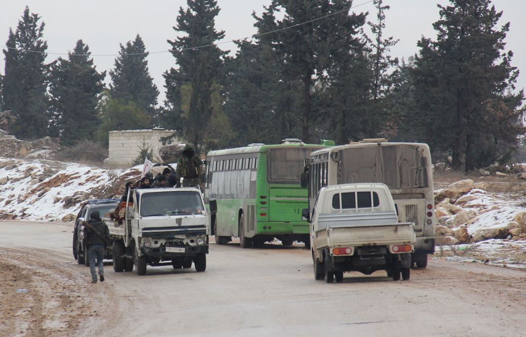 Vehicles carrying Syrians who are being evacuated from the rebel-held Shiite majority towns of Fuaa and Kafraya (R) into government controlled area, and others leaving Aleppo towards rebel-held territory (L), cross each on the road in a rebel-held territo