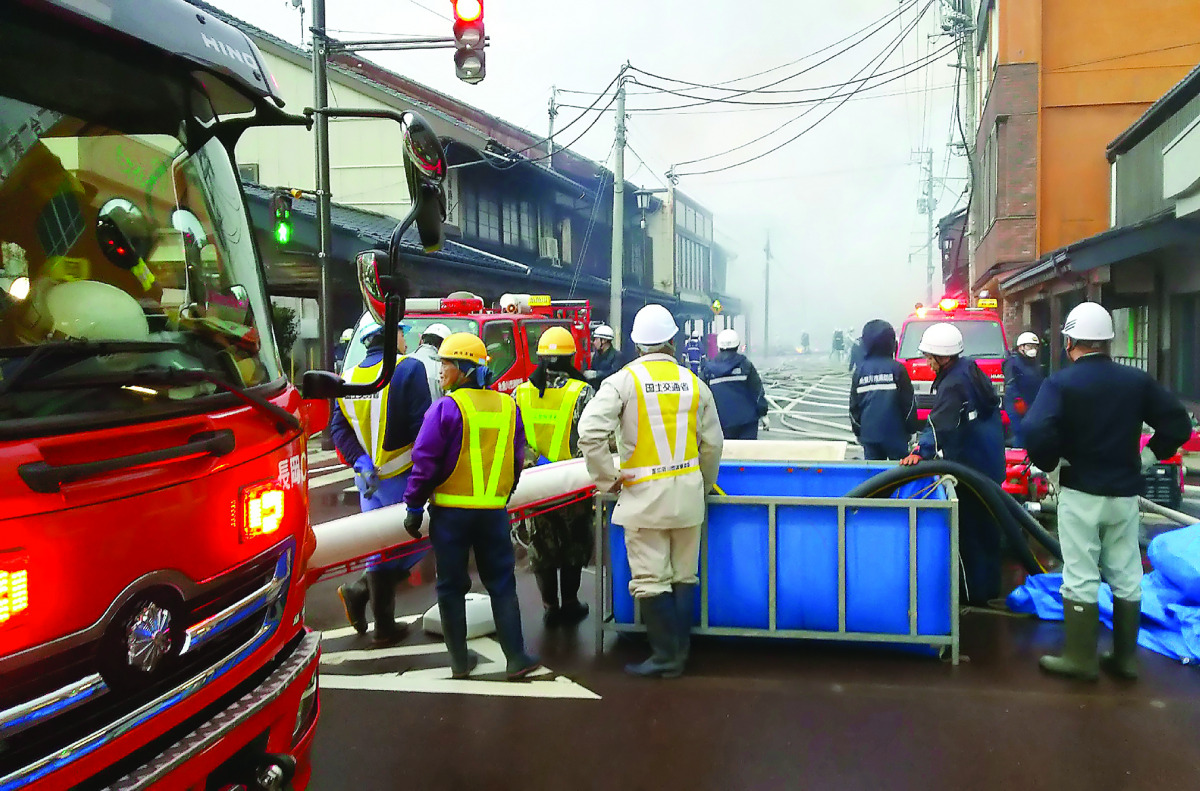 Residents look at firefighters at the scene of a blaze,  near JR Itoigawa Station, Niigata Prefecture, in Japan, yesterday. 