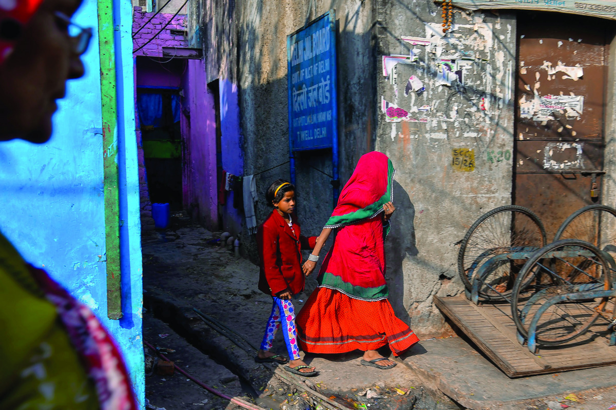 A young girl and her mother walks out of an alley in the Kathputli Colony in New Delhi, yesterday.