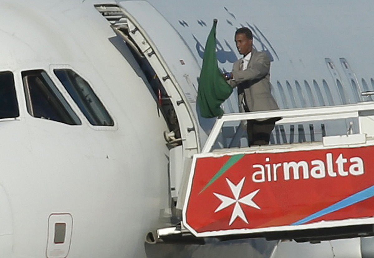 One of the hijackers of a Libyan Afriqiyah Airways Airbus A320 waves a Gaddafi-era Libyan flag at Malta Airport, December 23, 2016. REUTERS/Darrin Zammit