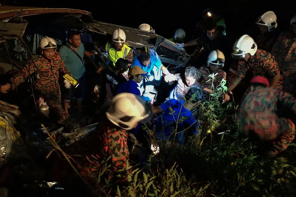 This handout from Malaysia Fire and Rescue Department taken on December 24, 2016 shows rescuers helping a bus crash survivor in Muar, outside Kuala Lumpur. AFP PHOTO / MALAYSIA FIRE AND RESCUE DEPARTMENT