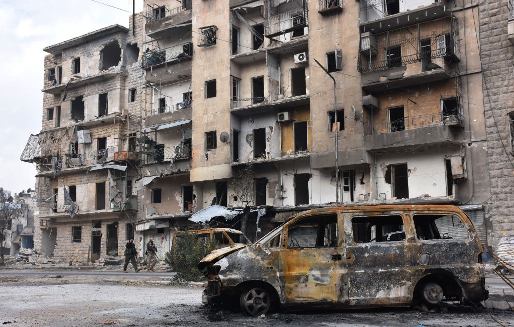 Syrians government forces walk past destroyed buildings in the former rebel-held Ansari district in the northern Syrian city of Aleppo on December 23, 2016 after regime forces retook control of the whole embattled city.  AFP / George OURFALIAN