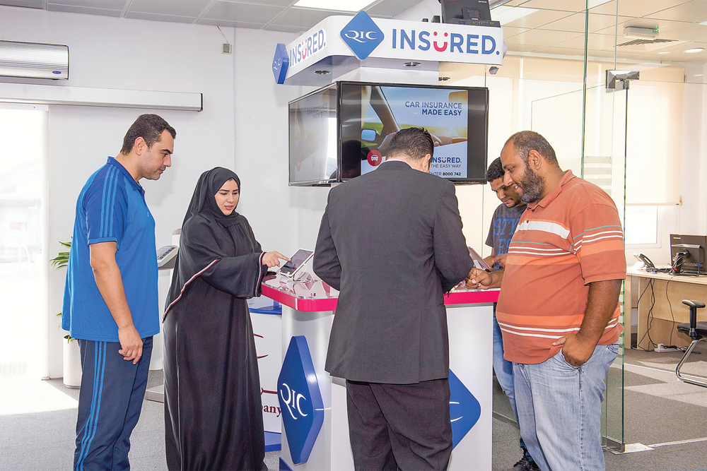 A QIC Insured staff assisting customers at  a Self Service counter in Abu Hamour. 