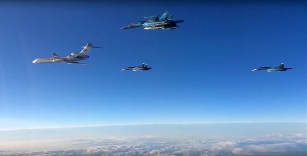 (FILES) This file video grab made on March 15, 2016 shows an image taken from a footage made available on the Russian Defence Ministry's official website reportedly showing Russian Su-34 bombers and a Tupolev Tu-154 transport plane (L) flying above an unk