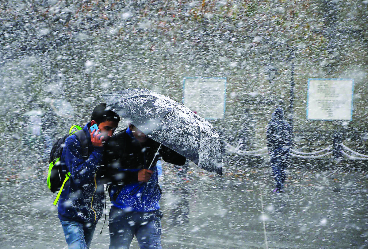 Pedestrians shelter under an umbrella as they walk through heavy snowfall on a road in Shimla, yesterday.