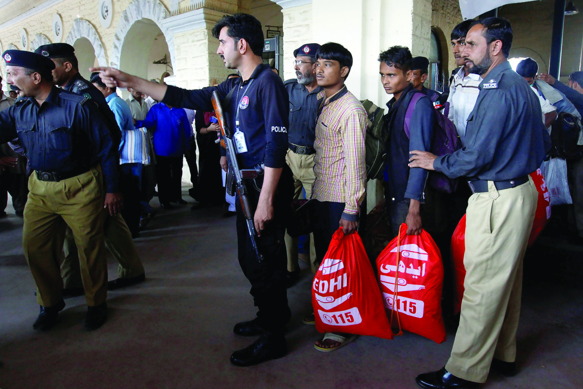 Fishermen from India are guided by policemen after they were released from a prison, at Cantonment railway station in Karachi, yesterday.
