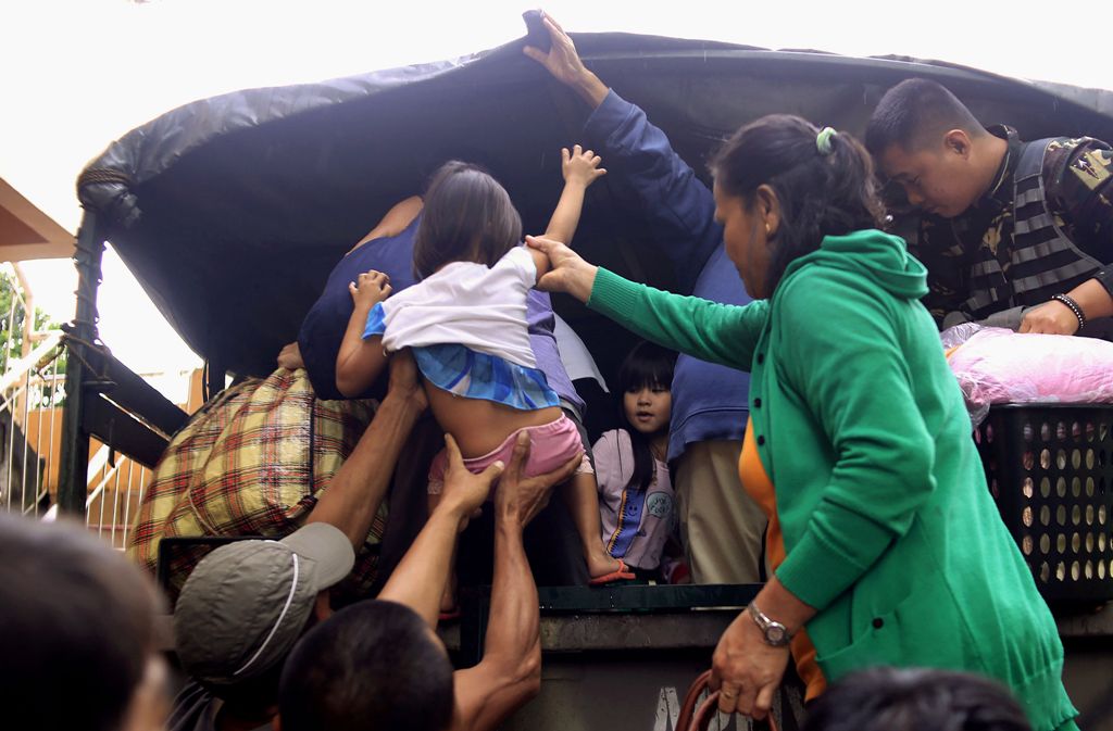 Residents are assisted into a truck after the local government implemented preemptive evacuations at Barangay Matnog, Daraga, Albay province on December 25, 2016, due to the approaching typhoon Nock-Ten.  AFP
