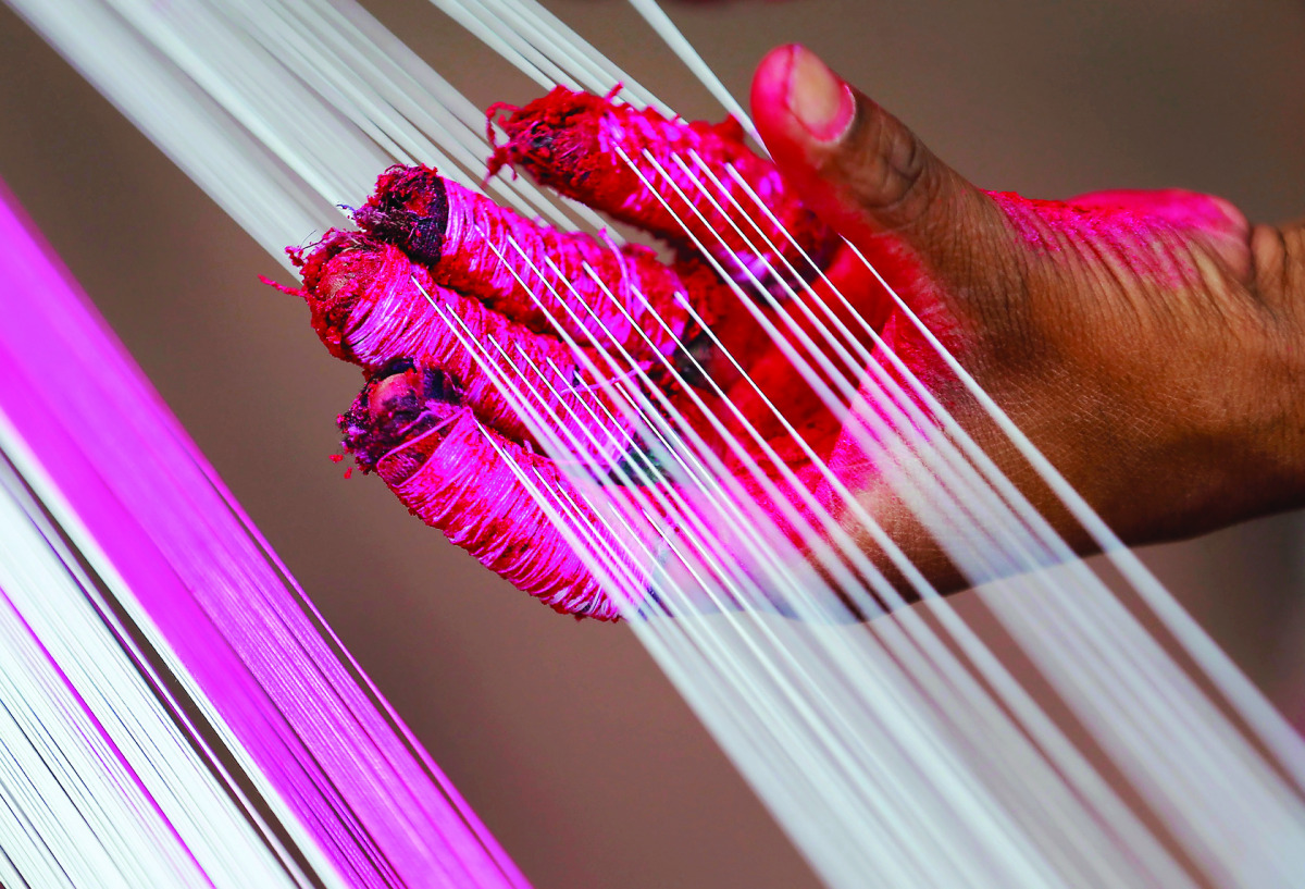 A worker applies colour to strings which will be used to make kites, alongside a road in Ahmedabad, yesterday. The 2017 Kite Festival Celebration is set to mark from January 7 to 15.