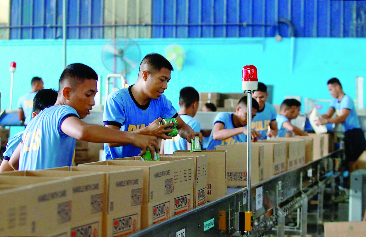 Personnel from the Philippine National Police (PNP) pack boxes with relief goods.