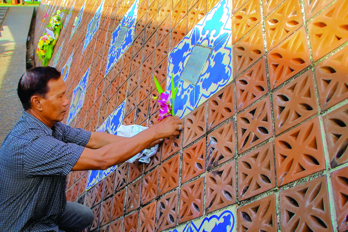 A man places flowers on a wave-shapedtsunami monument for victims of the 2004 tsunami in Ban Nam Khem, in Phang Nga Province, Thailand,  yesterday.