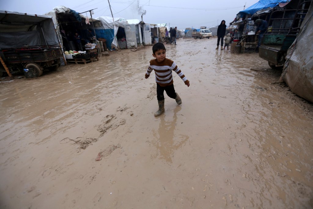 An internally displaced Syrian boy walks over rainwater in the Bab Al-Salam refugee camp, near the Syrian-Turkish border, northern Aleppo province, Syria December 26, 2016. REUTERS/Khalil Ashawi