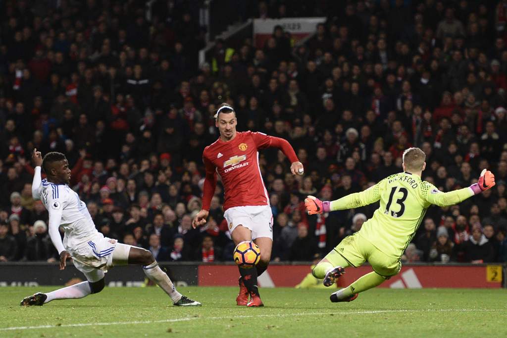 Manchester United's Swedish striker Zlatan Ibrahimovic (C) lifts the ball over Sunderland's English goalkeeper Jordan Pickford (R) to score their second goal during the English Premier League football match between Manchester United and Sunderland at Old 