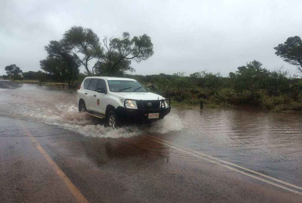 A four-wheel-drive vehicle drives through floodwater caused by heavy rain near the famous Uluru rock formation in central Australia, December 26, 2016. Parks Australia/Handout via REUTERS