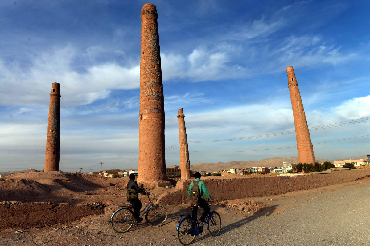 Afghan youths ride their bicycles past the historic minarets of Herat province (AFP) 