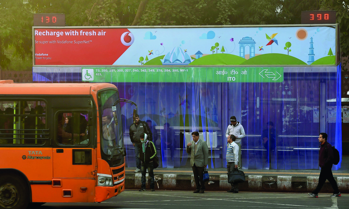 Commuters waiting for their ride at a bus stop where air purifiers have been installed  in New Delhi, yesterday. 