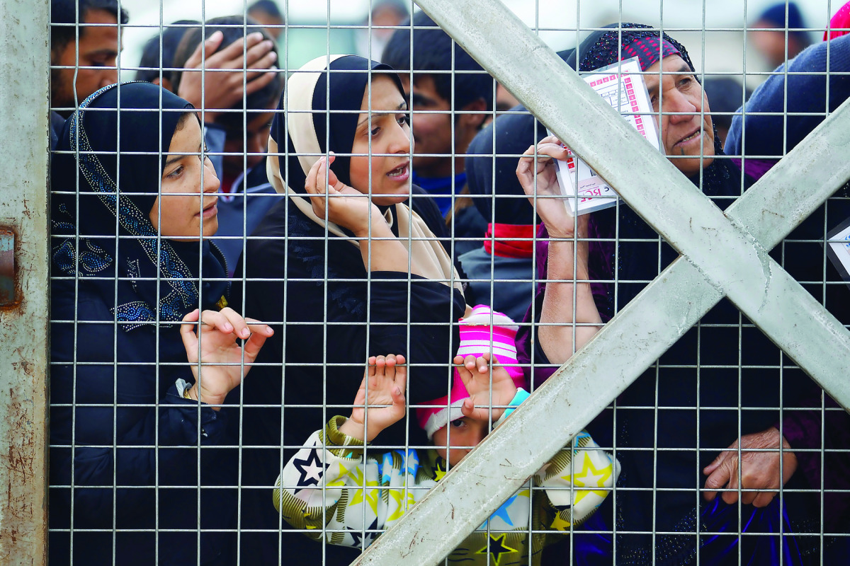 Displaced women, who fled the Islamic State (IS) stronghold of Mosul, stand behind the fence to receive aid at Hassan Sham camp, east of Mosul, Iraq, yesterday.
