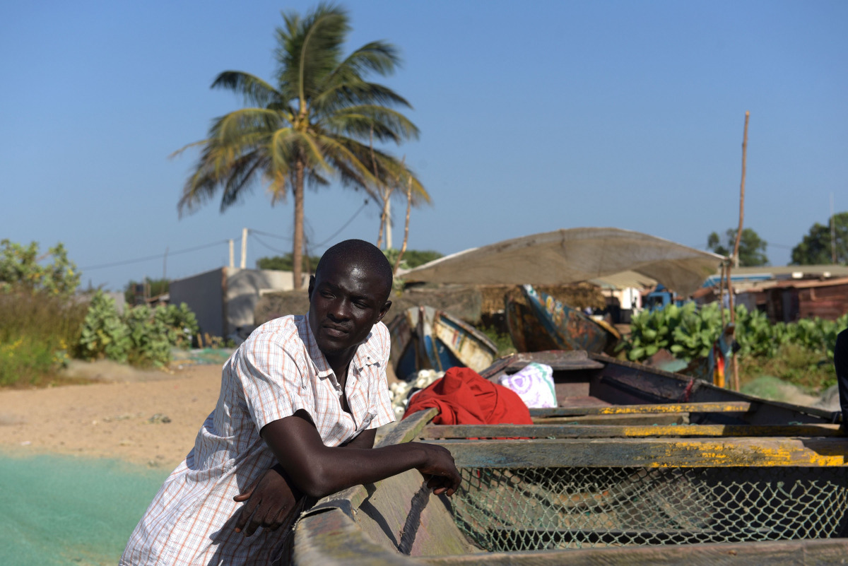 Gambian Ansu Sanyang poses next to a dugout on the beach in the village of Sanyang on December 4, 2016. Ansu Sanyang was ready. Sick of providing so little for his parents and sisters with any work he could find, the young Gambian resolved to take the mig