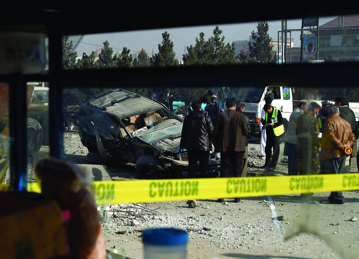 Afghan security personnel inspect a damaged vehicle after a roadside bomb explosion in Kabul, yesterday.