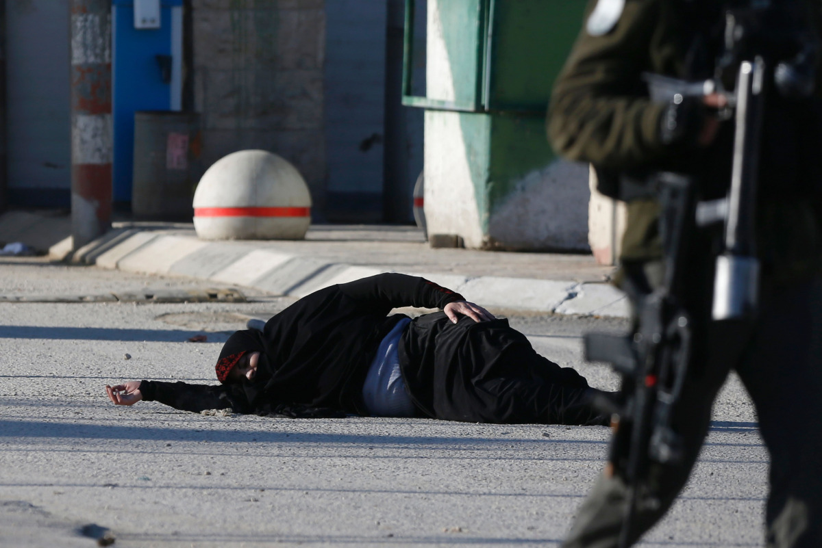 A Palestinian woman lies on the ground after she was shot and wounded by Israeli security forces while approaching the Qalandia checkpoint with a knife, between Jerusalem and the occupied West Bank on December 30, 2016, according to Israeli police. AFP / 