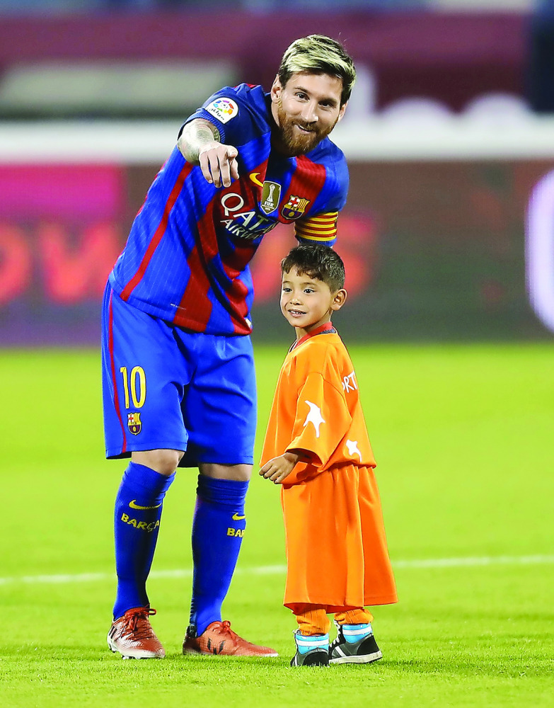 Barcelona's Lionel Messi talks to his Afghan superfan Murtaza Ahmadi on the pitch before the start of their friendly match against Saudi Arabia's  Al Ahli FC in this December 13  file photo.
