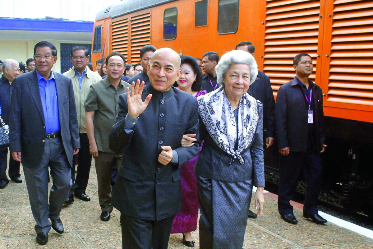 Cambodia's King Norodom Sihamoni and his mother former queen Monique (center R) walk as Cambodia's Prime Minister Hun Sen (far L) accompanies them at the railway station in Phnom Penh on December 30, 2016. Cambodian King Norodom Sihamoni took the train fr