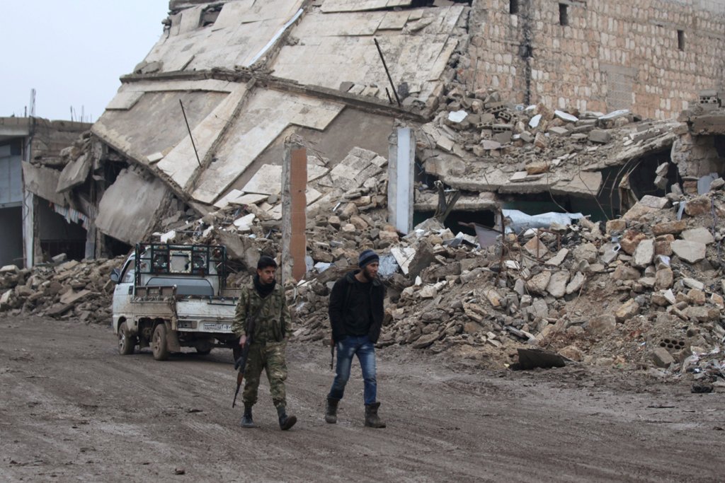 Rebel fighters walk near damaged buildings in al-Rai town, northern Aleppo countryside, Syria December 30, 2016. REUTERS/Khalil Ashawi
