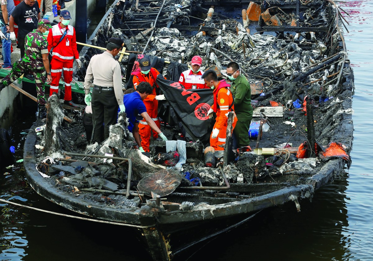 Red Cross and rescue workers on the charred boat, at Muara Angke port in Jakarta, Indonesia, yesterday.