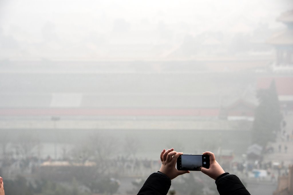 A person takes pictures with a mobile phone of city scenery during a hazy day in Beijing, China, January 1, 2017. Picture taken January 1, 2017. REUTERS/Stringer 