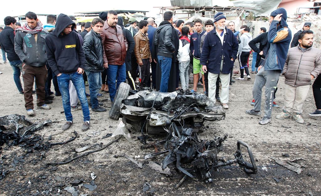 Iraqis inspect a charred vehicle on the site of a bomb attack in Sadr City, a majority Shiite neighbourhood in the northeast of the capital Baghdad, on January 2, 2017.  AFP / SABAH ARAR
