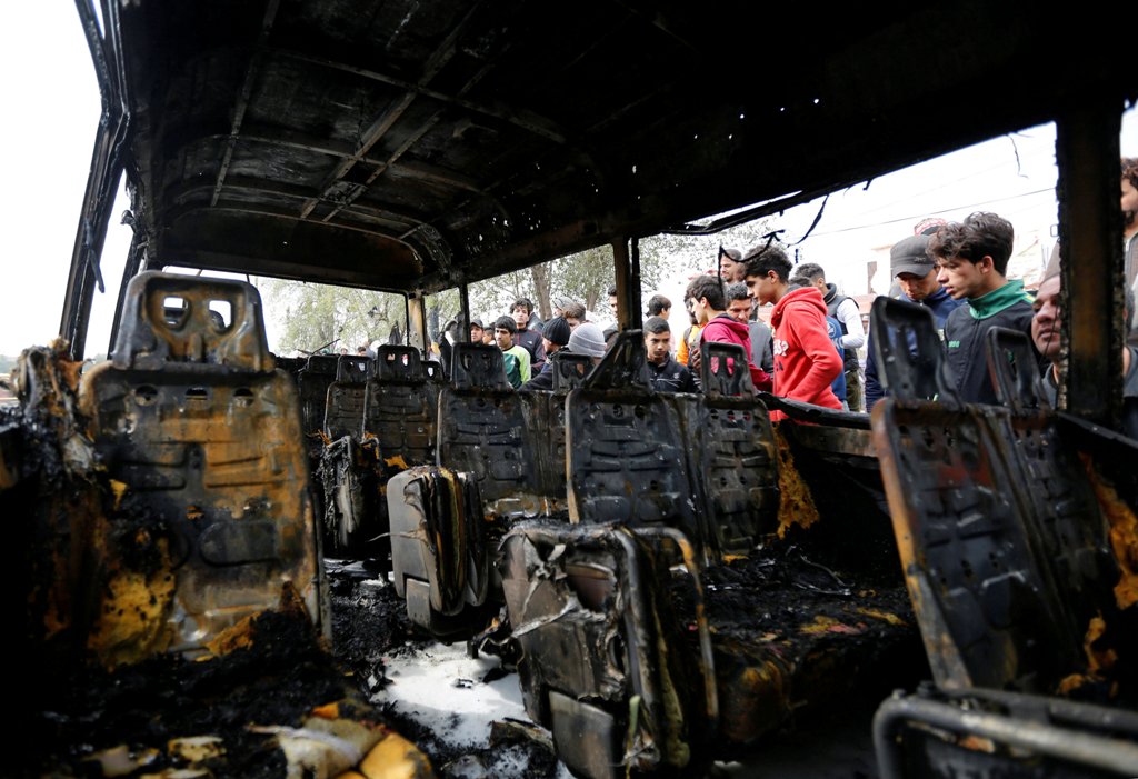 People look at a burned vehicle at the site of car bomb attack in a busy square at Baghdad's sprawling Sadr City district, in Iraq January 2, 2017. REUTERS/Ahmed Saad.