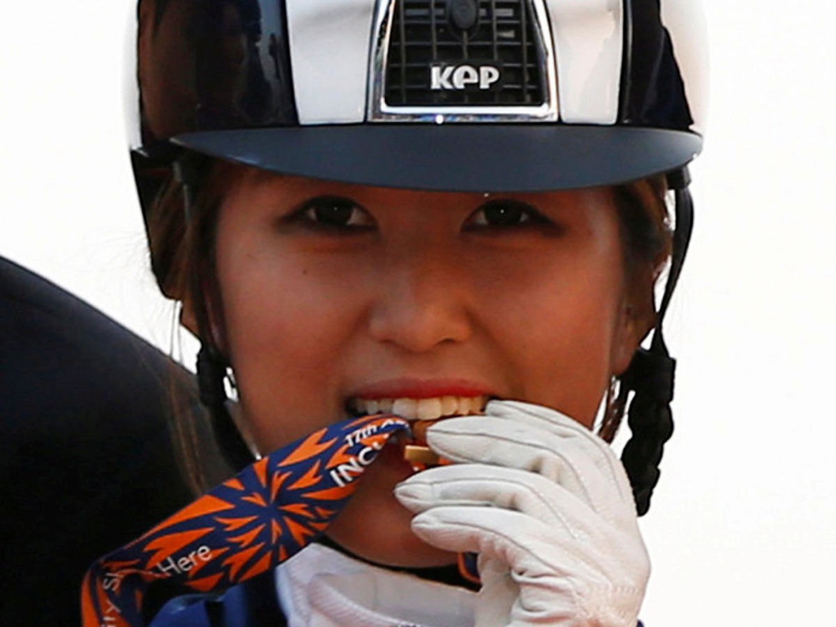 FILE PHOTO: South Korea's Chung Yoo-ra, then known as Chung Yoo-yeon, bites her gold medal as she poses after winning the equestrian Dressage Team competition at the Dream Park Equestrian Venue during the 17th Asian Games in Incheon September 20, 2014. RE