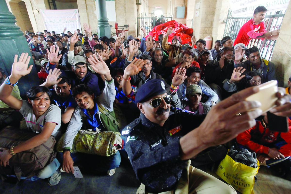 Fishermen from India who were held captive for crossing territorial waters wave for a selfie by a policeman after their release, at Cantonment railway station in Karachi, yesterday.