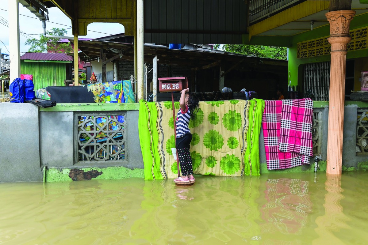 A girl stands on a mailbox outside her house in Malaysia's northeastern town of Rantau Panjang, yesterday.