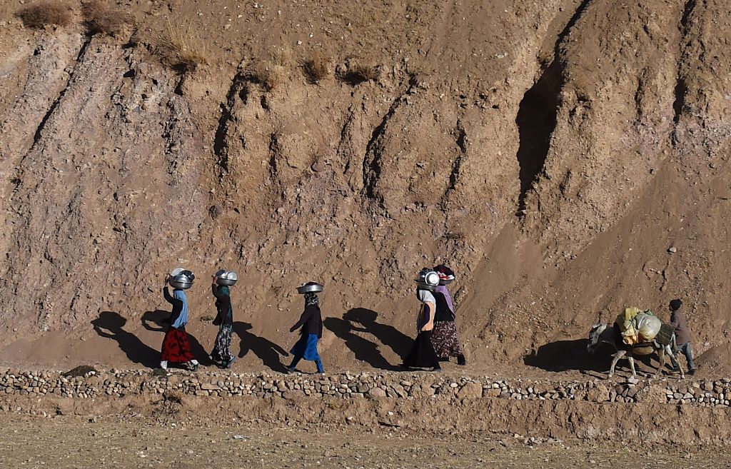 In this photograph taken on November 5, 2016, a group of Afghan Hazara women carry washed utensils as they walk home in the Yakawlang District of Bamiyan Province.  AFP / Wakil KOHSAR