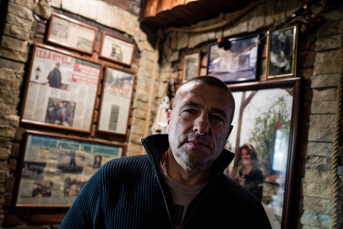 Renato Grbic, a Belgrade fisherman and restaurant owner, poses for a picture in front of newspaper articles about him and his suicide rescues, in Belgrade on December 21, 2016. Over the span of nearly two decades, Grbic, 55, has rescued 29 people who have