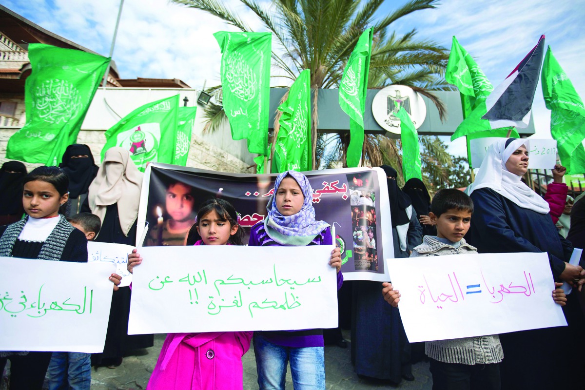Palestinian children part in a protest against ongoing electricity shortages, with the flags of Islamist movement Hamas waving behind, in Gaza City on January 10, 2017. The signs in Arabic read (R-L): 