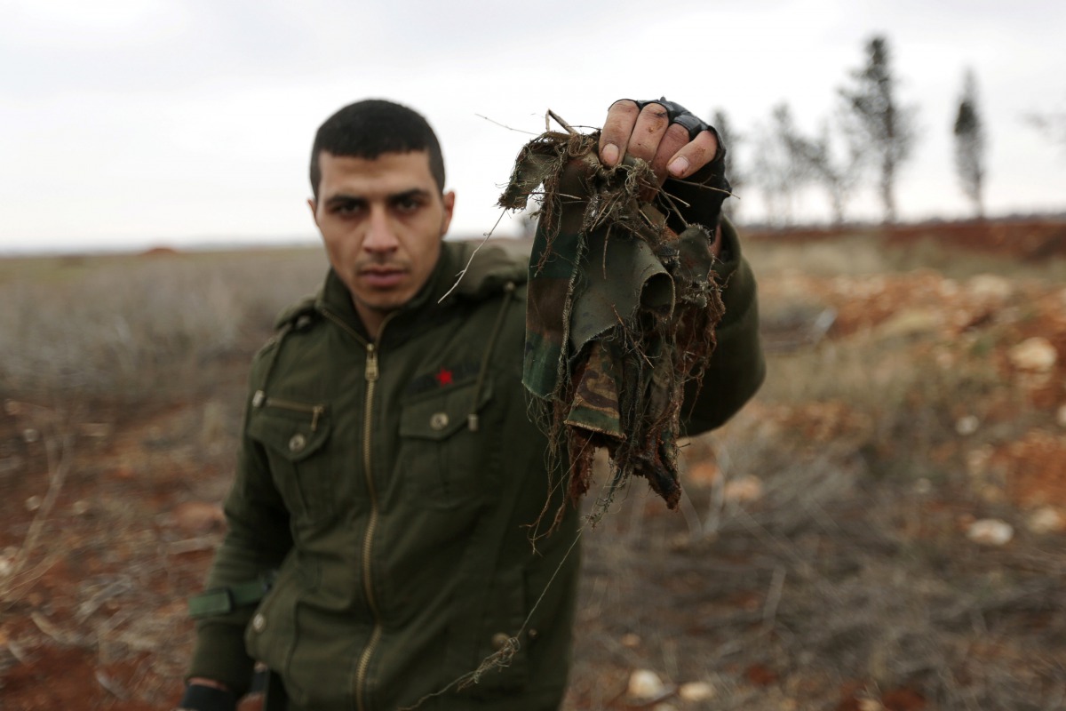 Ahmad Najjar, a 27 year-old Free Syrian Army fighter, holds a torn camouflage rags he said had clothed one of two colleagues recently blown up trying to dismantle explosives planted by the Islamic State fighters, on the outskirts of the northern Syrian to